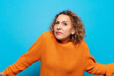 middle age woman feeling clueless and confused, having no idea, absolutely puzzled with a dumb or foolish look