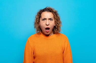 Orta yaşlı bir kadın şok olmuş, kızgın, sinirli ya da hayal kırıklığına uğramış, ağzı açık ve öfkeli görünüyor.