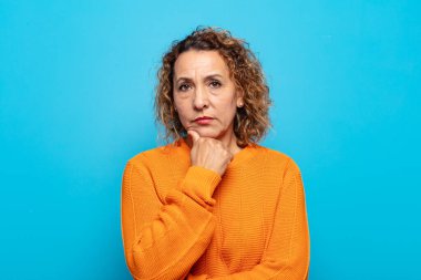 Orta yaşlı kadın ciddi görünüyor, kafası karışık, kararsız ve düşünceli, seçenekler ve seçenekler arasında şüpheci.