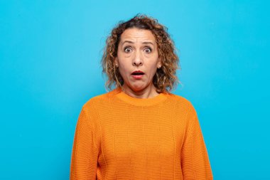 Orta yaşlı kadın korkmuş ve şok olmuş hissediyor, ağzı açık şaşkınlık içinde.