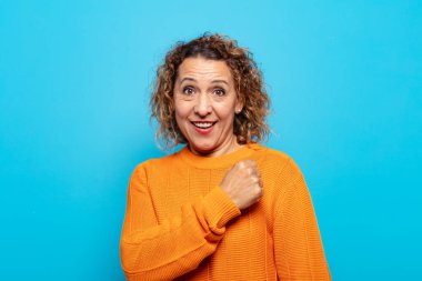 Orta yaşlı bir kadın mutlu, pozitif ve başarılı hissediyor, bir meydan okumayla karşılaştığında motive oluyor veya iyi sonuçları kutluyor.