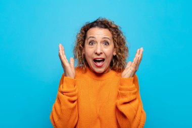 Orta yaşlı bir kadın beklenmedik bir sürpriz yüzünden şaşkın, heyecanlı, gülen, şaşkın ve mutlu hissediyor.