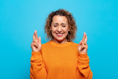 Orta yaşlı bir kadın gergin ve umutlu, şans diliyor ve dua ediyor.