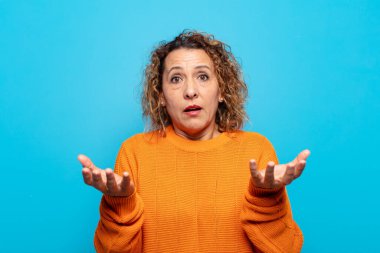 Orta yaşlı bir kadın son derece şok olmuş, şaşırmış, endişeli ve paniklemiş, stresli ve dehşete kapılmış bir şekilde bakıyor.