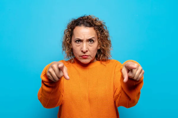 Orta yaşlı bir kadın kameraya iki parmağını ve kızgın bir ifadeyle bakarak sana görevini yapmanı söylüyor.