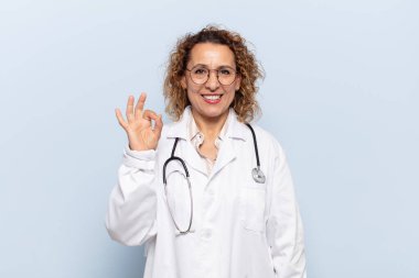 İspanyol orta yaşlı kadın mutlu, rahat ve tatmin olmuş hissediyor. Onayını iyi bir hareketle gösteriyor. Gülümsüyor.