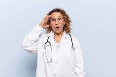 İspanyol orta yaşlı kadın mutlu, şaşkın ve şaşırmış görünüyor, gülümsüyor ve inanılmaz ve inanılmaz iyi haberleri fark ediyor.