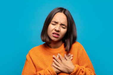 İspanyol kadın üzgün, yaralı ve kalbi kırık görünüyor, iki elini de kalbe yakın tutuyor, ağlıyor ve bunalımda.