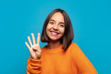 İspanyol kadın gülümsüyor ve arkadaş canlısı görünüyor. Elleri önde, geriye doğru sayıyor.