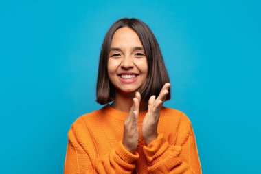 İspanyol kadın kendini mutlu ve başarılı hissediyor, gülümsüyor ve alkışlıyor, alkışlarla tebrik ediyor.