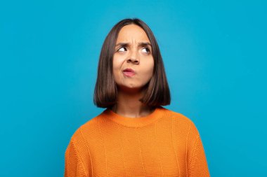 İspanyol kadın şaşkın ve şaşkın görünüyor, merak ediyor ya da bir sorunu çözmeye çalışıyor ya da düşünüyor.