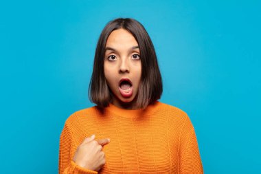 İspanyol kadın şok olmuş ve şaşırmış görünüyor, ağzı açık, kendini işaret ediyor.