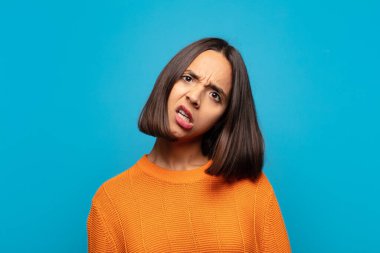 hispanic woman feeling puzzled and confused, with a dumb, stunned expression looking at something unexpected