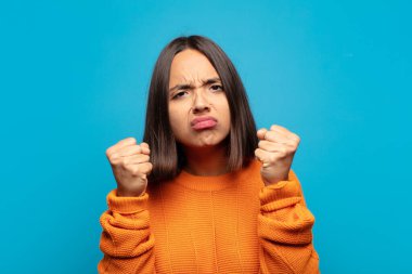 İspanyol kadın kendinden emin, sinirli, güçlü ve agresif görünüyor. Yumrukları boks pozisyonunda dövüşmeye hazır.