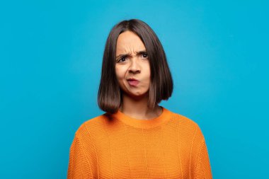 Hispanik kadın kendini şaşkın ve şüpheli hissediyor, merak ediyor ya da karar vermeye çalışıyor.