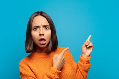 İspanyol kadın şaşkın ve şaşırmış hissediyor. Kenardaki fotokopi alanını işaret ediyor. Şaşırmış, ağzı açık bir bakışla.