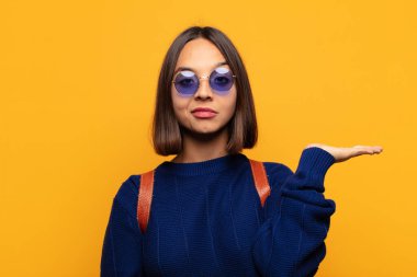 İspanyol kadın gülümsüyor, kendinden emin, başarılı ve mutlu hissediyor, fotokopi alanında fikir veya konsept gösteriyor.