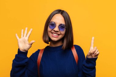 İspanyol kadın gülümsüyor ve arkadaş canlısı görünüyor, 6 ya da 6 numarayı gösteriyor, elleri önde, geri sayıyor.