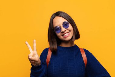 İspanyol kadın gülümsüyor ve arkadaş canlısı görünüyor. İki ya da iki numarayı gösteriyor. Elleri önde, geri sayıyor.