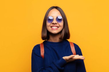 İspanyol kadın mutlu bir şekilde gülümsüyor, mutlu hissediyor ve fotokopi uzayında bir konsept gösteriyor.