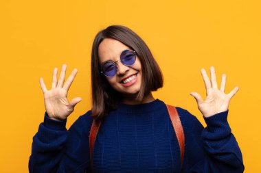 İspanyol kadın gülümsüyor ve arkadaş canlısı görünüyor, onuncu ya da onuncu numarayı gösteriyor, eli önde, geri sayıyor.