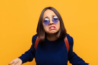 hispanic woman feeling clueless and confused, having no idea, absolutely puzzled with a dumb or foolish look