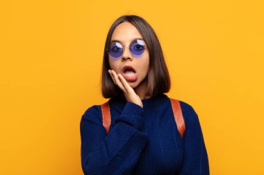 İspanyol kadın şok ve inançsızlıkla ağzı açık, elleri yanak ve kolları çaprazlanmış, sersemlemiş ve şaşırmış hissediyor.