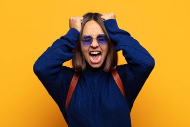 İspanyol kadın stresli ve endişeli, depresif ve hayal kırıklığına uğramış hissediyor, iki elini de başa kaldırıyor.