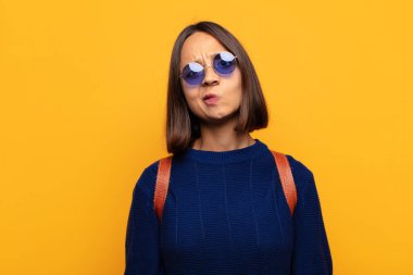 Hispanik kadın kendini şaşkın ve şüpheli hissediyor, merak ediyor ya da karar vermeye çalışıyor.