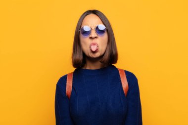 İspanyol kadın tiksinmiş ve rahatsız olmuş hissediyor, dilini dışarı çıkarıyor, iğrenç ve iğrenç bir şeyden hoşlanmıyor.