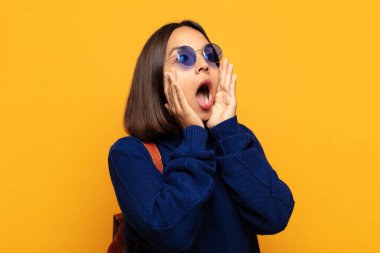 Hispanik kadın mutlu, heyecanlı ve şaşırmış hissediyor, iki eli yüzü yana bakıyor