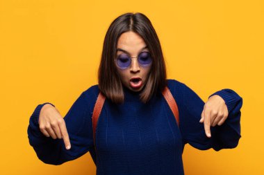 İspanyol kadın şok olmuş, ağzı açık ve şaşırmış hissediyor. İnançsızlık ve şaşkınlık içinde bakıyor ve onu işaret ediyor.