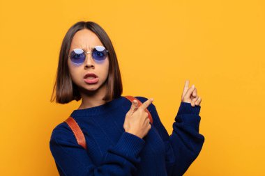 İspanyol kadın şaşkın ve şaşırmış hissediyor. Kenardaki fotokopi alanını işaret ediyor. Şaşırmış, ağzı açık bir bakışla.