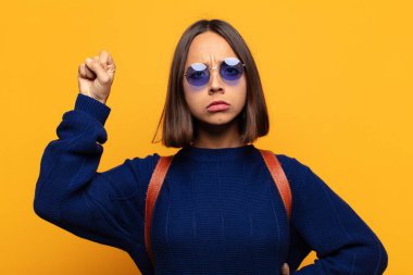 Hispanik kadın ciddi, güçlü ve asi hissediyor, yumruğunu kaldırıyor, protesto ediyor ya da devrim için savaşıyor.