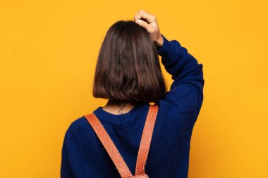 İspanyol kadın bilgisiz ve kafası karışık, bir çözüm düşünüyor, eli kalçasında, diğeri kafasında, dikiz aynasından.