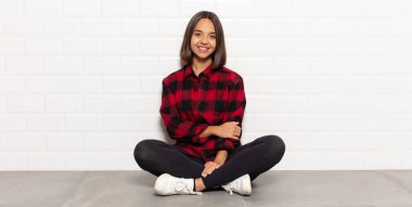 İspanyol kadın utangaç ve neşeli bir şekilde gülüyor, arkadaş canlısı ve olumlu ama güvensiz bir tavırla.