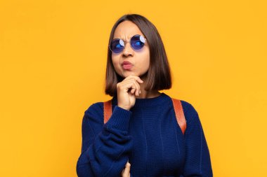 Hispanik kadın düşünceli, meraklı ya da hayal kuruyor, hayal kuruyor ve mekanı kopyalamak için yukarı bakıyor.