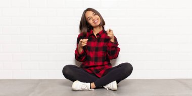 İspanyol kadın mutlu ve kendinden emin hissediyor, kamerayı iki eliyle gösteriyor ve gülüyor, seni seçiyor.