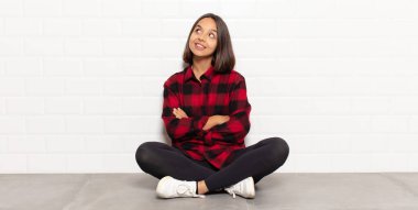 İspanyol kadın kendini mutlu, gururlu ve umutlu hissediyor, merak ediyor ya da düşünüyor, çapraz kollarla boşluğu doldurmaya çalışıyor.