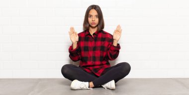 İspanyol kadın ciddi, mutsuz, kızgın ve hoşnutsuz görünüyor. Girmeyi yasaklıyor ya da her iki avuçta da dur diyor.