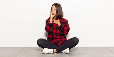 Boğazı ağrıyan ve grip belirtileri gösteren ağzı kapalı öksüren İspanyol bir kadın.