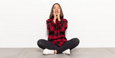 İspanyol kadın mutlu, heyecanlı ve pozitif hissediyor. Elleri ağızda, bağırarak bağırıyor.