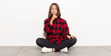 İspanyol kadın ciddi görünüyor ve parmaklarını dudaklarına bastırıp sessizlik ya da sessizlik talep ediyor, sır saklıyor.