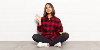 İspanyol kadın mutlu ve neşeli bir şekilde gülümsüyor, el sallıyor, seni selamlıyor ve selamlıyor, ya da hoşça kal diyor.