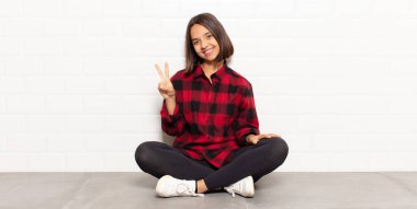 İspanyol kadın gülümsüyor ve arkadaş canlısı görünüyor. İki ya da iki numarayı gösteriyor. Elleri önde, geri sayıyor.