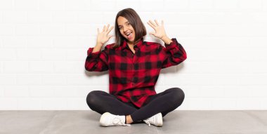 İspanyol kadın gülümsüyor ve arkadaş canlısı görünüyor, onuncu ya da onuncu numarayı gösteriyor, eli önde, geri sayıyor.