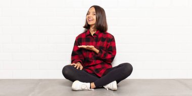 İspanyol kadın mutlu bir şekilde gülümsüyor, mutlu hissediyor ve fotokopi uzayında bir konsept gösteriyor.