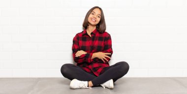 İspanyol kadın kollarını kavuşturup mutlu bir şekilde gülüyor, rahat, pozitif ve tatmin edici bir pozla.