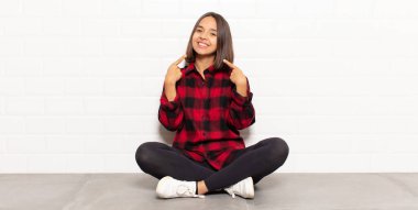 İspanyol kadın kendine güvenerek gülümsüyor. Kendi gülüşünü gösteriyor. Olumlu, rahat, tatmin olmuş tavır.