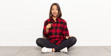 İspanyol kadın mutlu, gururlu ve şaşırmış görünüyor, neşeli bir şekilde kendini gösteriyor, kendinden emin ve kibirli hissediyor.